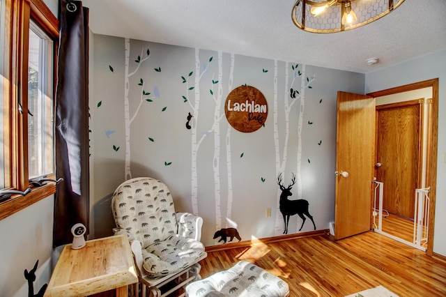 sitting room with baseboards, light wood-style flooring, and a textured ceiling