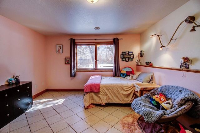 bedroom with light tile patterned floors, baseboards, and a textured ceiling