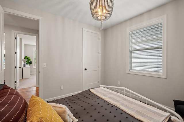 bedroom with an inviting chandelier, multiple windows, and baseboards