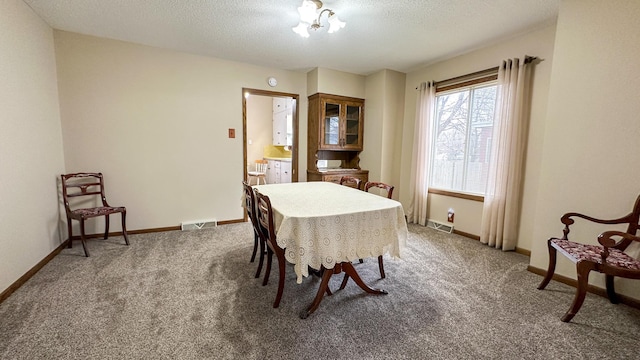 dining space featuring a textured ceiling, carpet flooring, visible vents, and baseboards