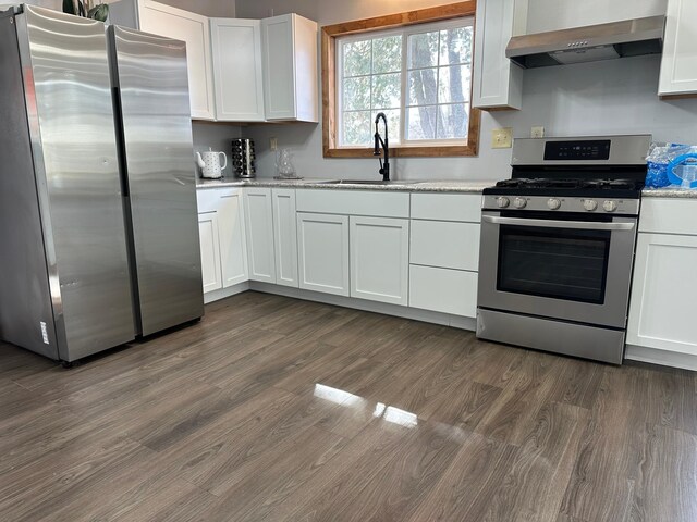 kitchen featuring a sink, dark wood finished floors, stainless steel appliances, wall chimney exhaust hood, and white cabinets