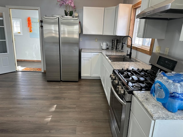 kitchen featuring dark wood finished floors, wall chimney exhaust hood, appliances with stainless steel finishes, and a sink