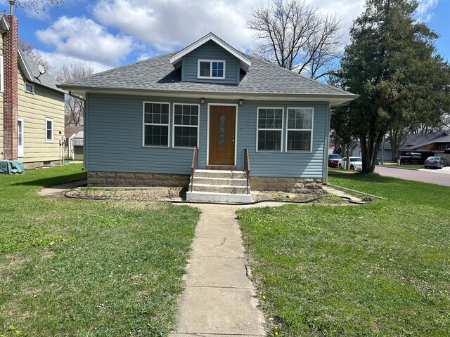 709 4th Ave, Windom, MN 56101 - bungalow-style house with entry steps, a front yard, and a shingled roof