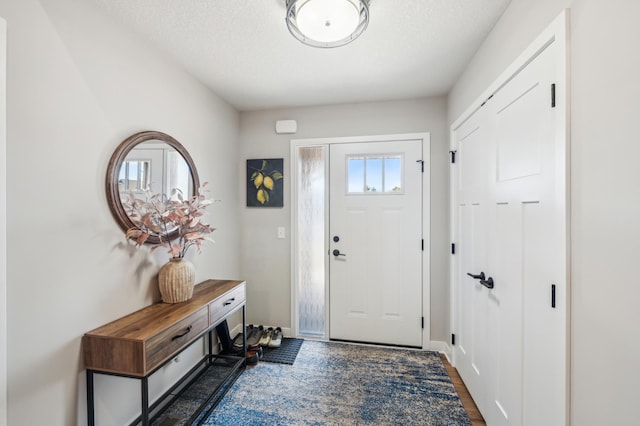 entrance foyer with baseboards, dark wood finished floors, and a textured ceiling