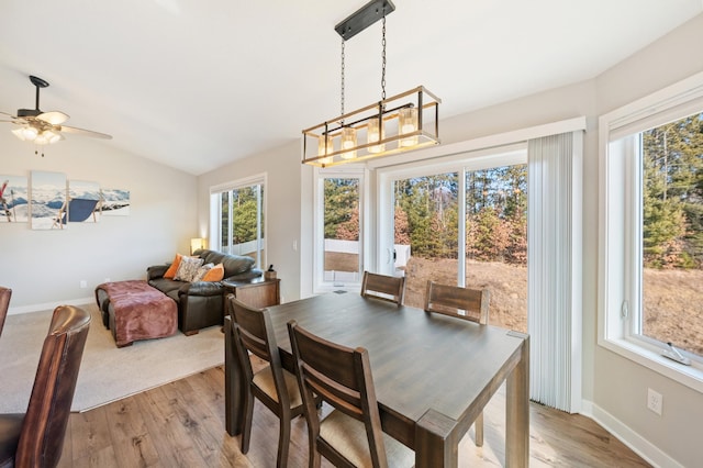 dining area featuring light wood-type flooring, baseboards, and vaulted ceiling