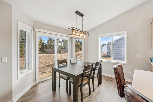 dining area with light wood finished floors, baseboards, and vaulted ceiling