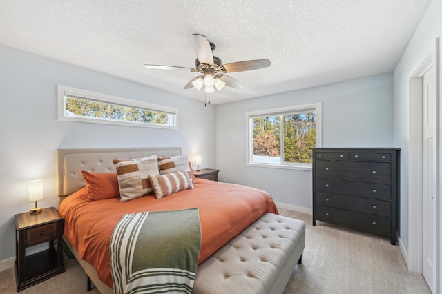 bedroom with light carpet, baseboards, and a textured ceiling