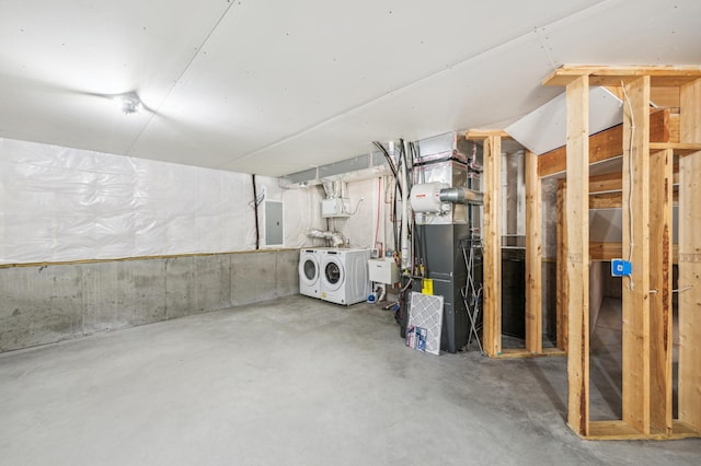 unfinished basement with a sink, washing machine and clothes dryer, electric panel, and heating unit