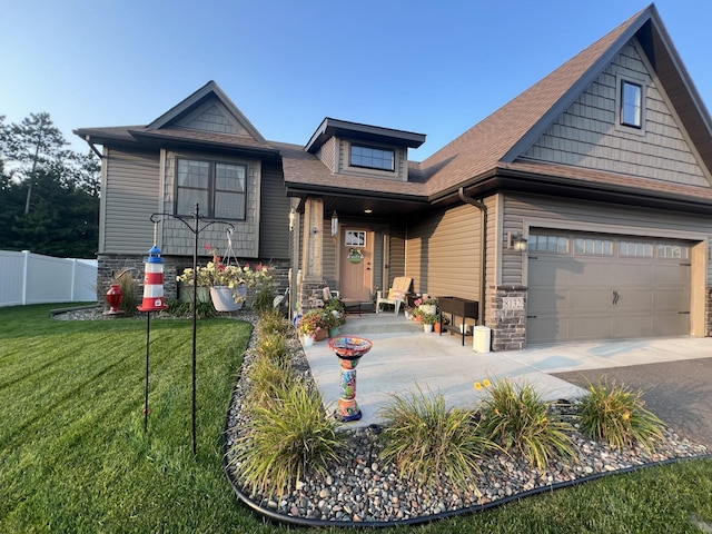 view of front facade with driveway, stone siding, fence, and a front yard