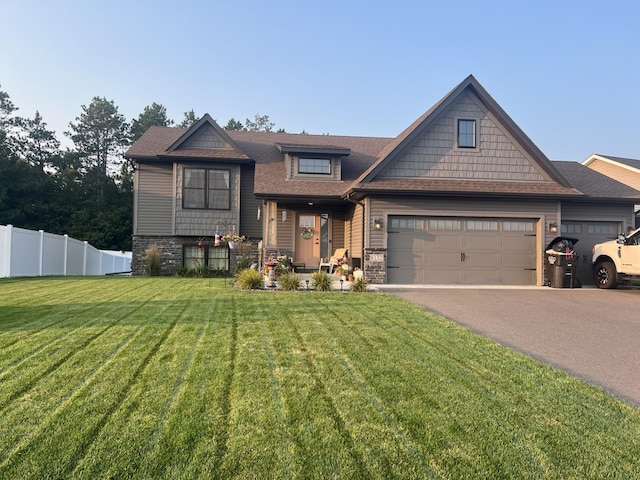 view of front of house featuring aphalt driveway, a shingled roof, a front yard, fence, and stone siding