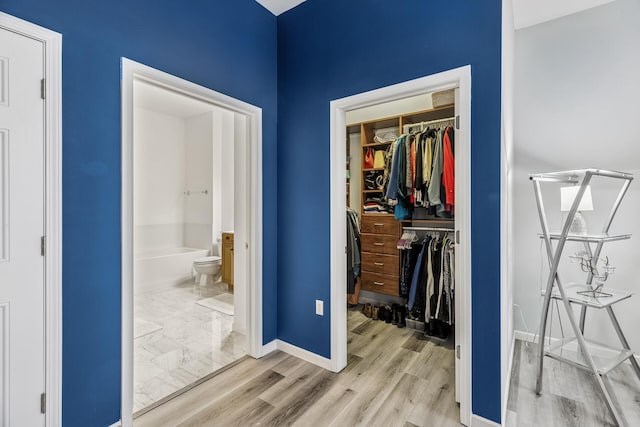 270 4th St E Unit 401, Saint Paul, MN 55101 - bedroom with a closet, baseboards, wood finished floors, a walk in closet, and connected bathroom
