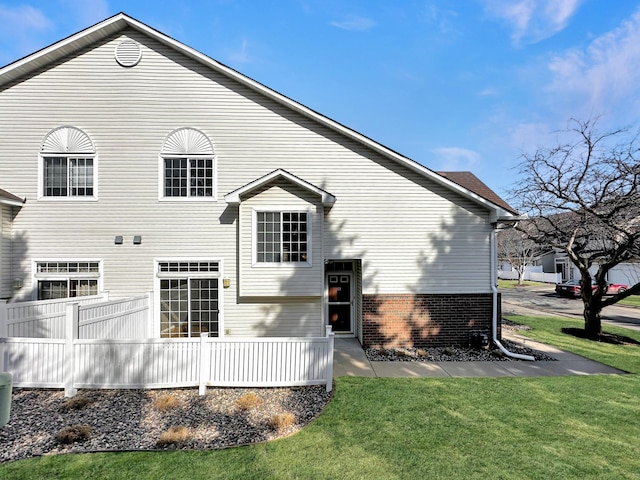 rear view of house featuring brick siding and a lawn