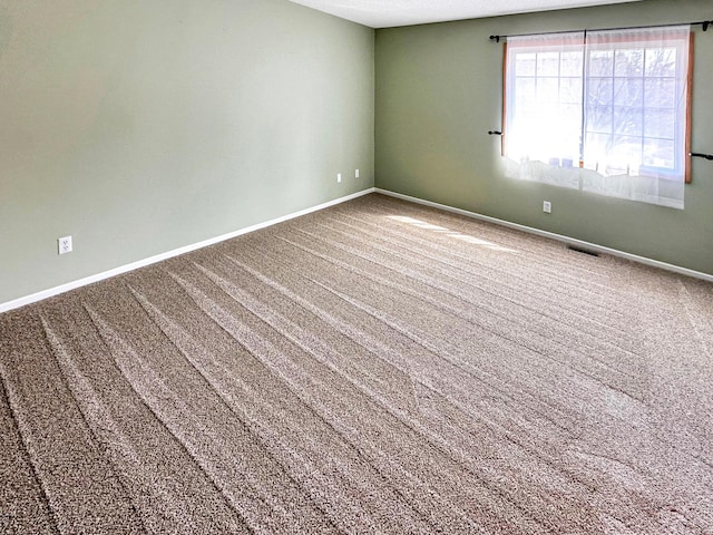 spare room featuring carpet flooring, visible vents, and baseboards