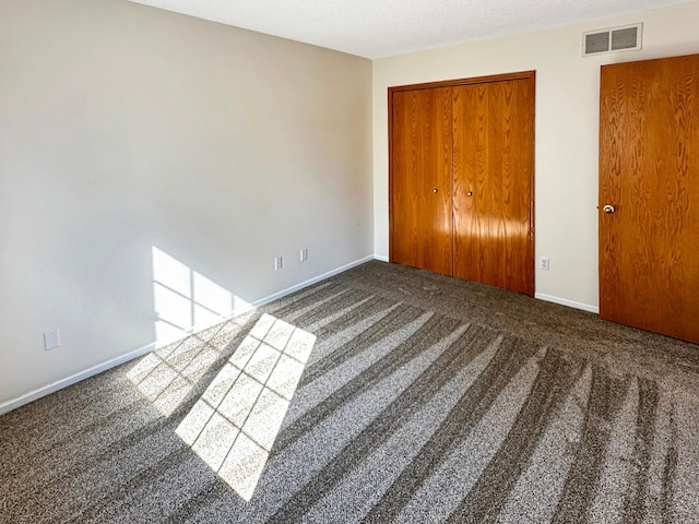 unfurnished bedroom featuring baseboards, carpet, visible vents, and a closet