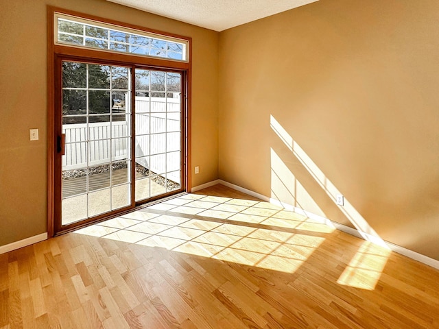 entryway with light wood-type flooring, a textured ceiling, and baseboards