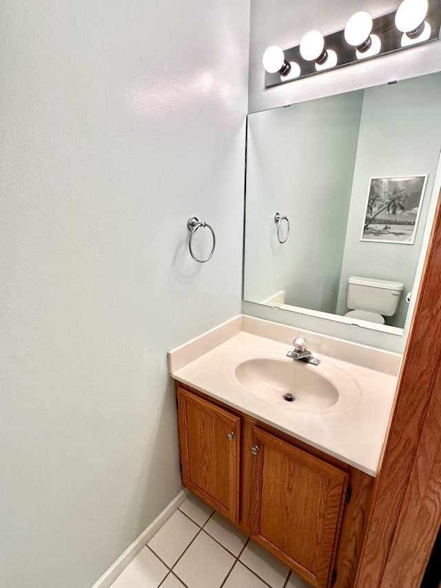 half bath featuring toilet, tile patterned floors, baseboards, and vanity