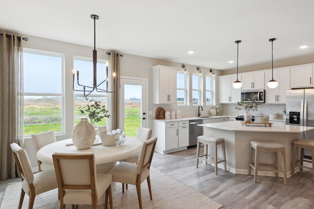 dining space with light wood-type flooring, an inviting chandelier, and recessed lighting