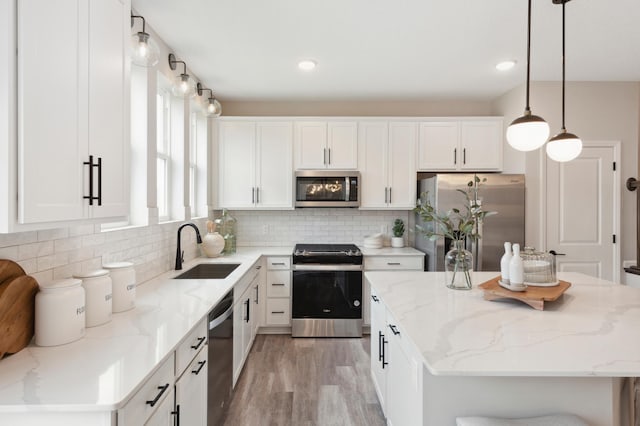 kitchen with a kitchen island, a sink, white cabinets, appliances with stainless steel finishes, and tasteful backsplash