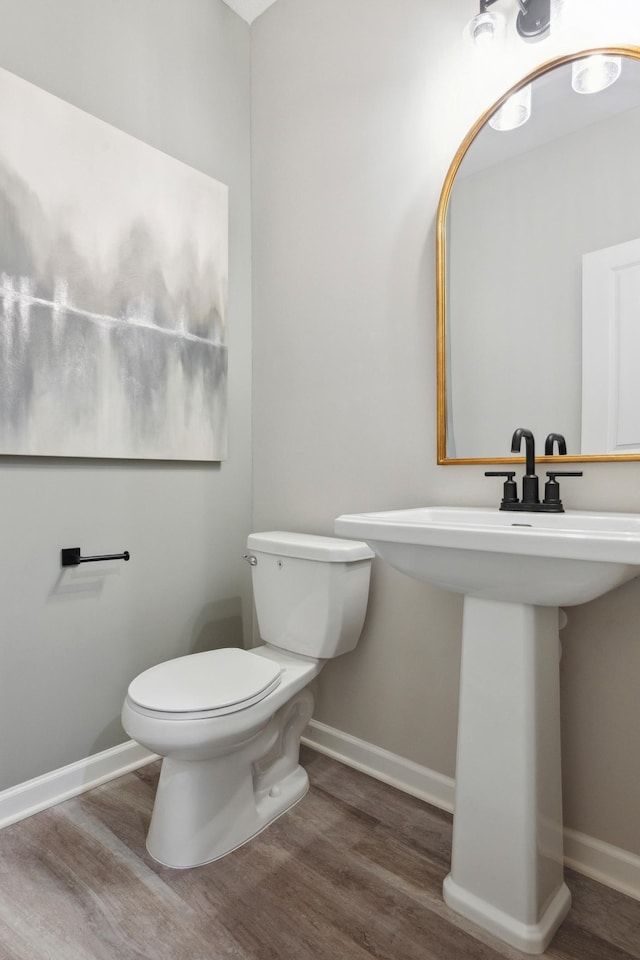 bathroom with toilet, baseboards, and wood finished floors