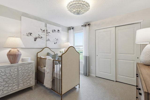 bedroom featuring a nursery area, a closet, carpet flooring, and a textured ceiling