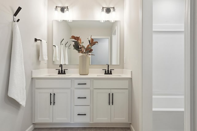 full bath featuring double vanity, a sink, and baseboards