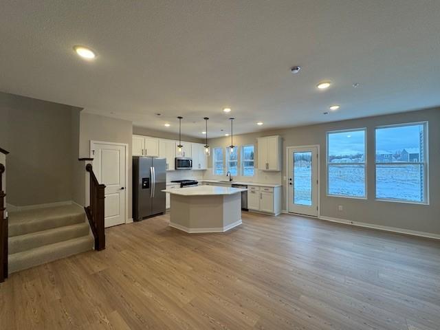 kitchen with a kitchen island, appliances with stainless steel finishes, open floor plan, light wood-type flooring, and a sink