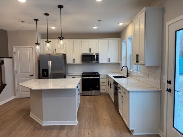 kitchen featuring appliances with stainless steel finishes, a center island, a sink, and light wood finished floors