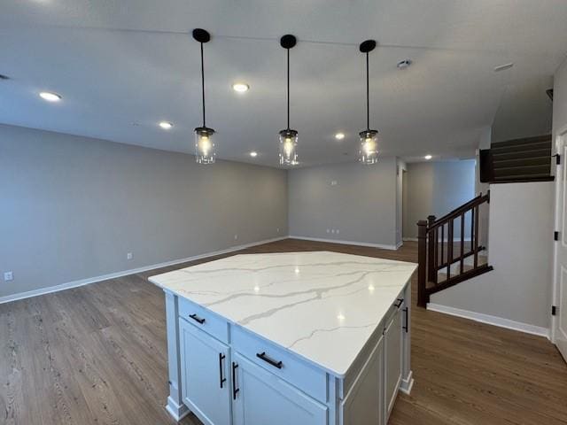 kitchen featuring hanging light fixtures, a kitchen island, baseboards, and wood finished floors