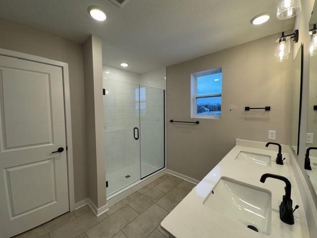 full bathroom with a stall shower, a sink, baseboards, and double vanity