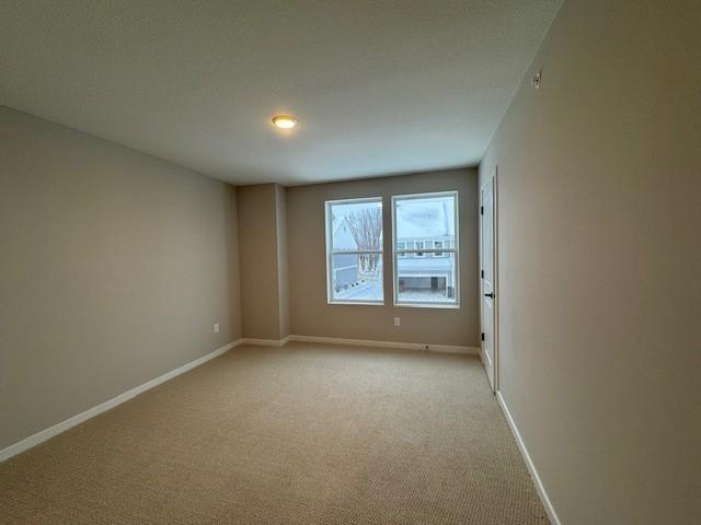 unfurnished room featuring light carpet and baseboards