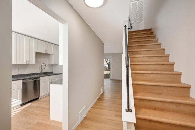 staircase featuring baseboards, visible vents, and wood finished floors