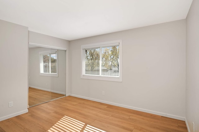 unfurnished bedroom featuring light wood-style floors, a closet, and baseboards