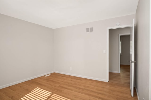 empty room featuring light wood-style flooring, visible vents, and baseboards