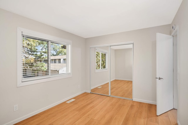 unfurnished bedroom with light wood-type flooring, a closet, visible vents, and baseboards