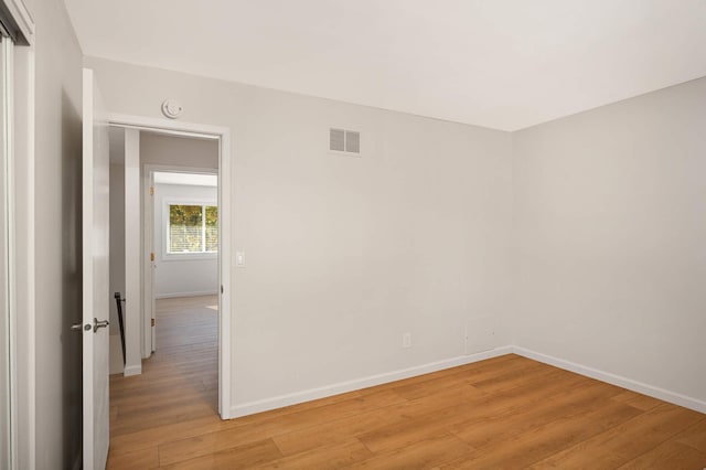 empty room with light wood-style flooring, visible vents, and baseboards