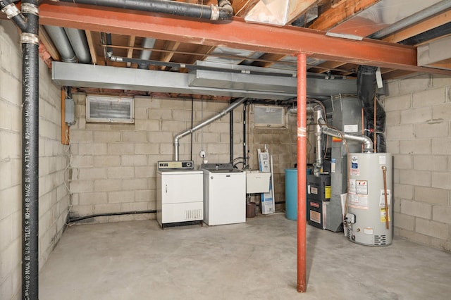 unfinished below grade area with a sink, water heater, gas water heater, and washing machine and dryer