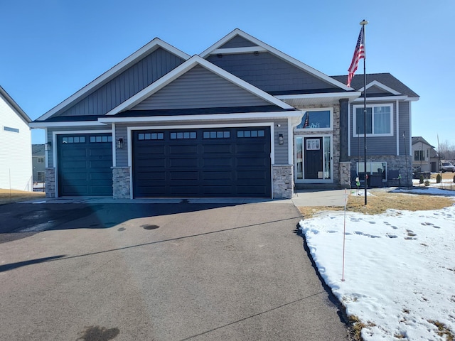 craftsman-style house featuring board and batten siding, an attached garage, stone siding, and driveway