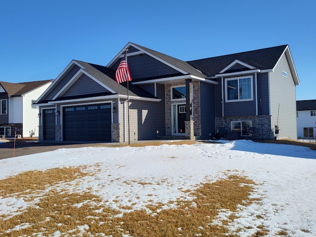 craftsman house featuring an attached garage, stone siding, and driveway