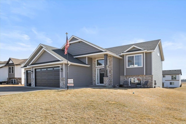 view of front of house with stone siding, driveway, an attached garage, and a front lawn