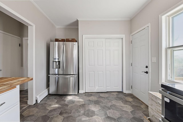 kitchen featuring baseboards, a baseboard radiator, ornamental molding, stainless steel appliances, and wood counters