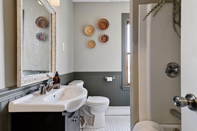 bathroom with tile patterned floors, toilet, and wainscoting