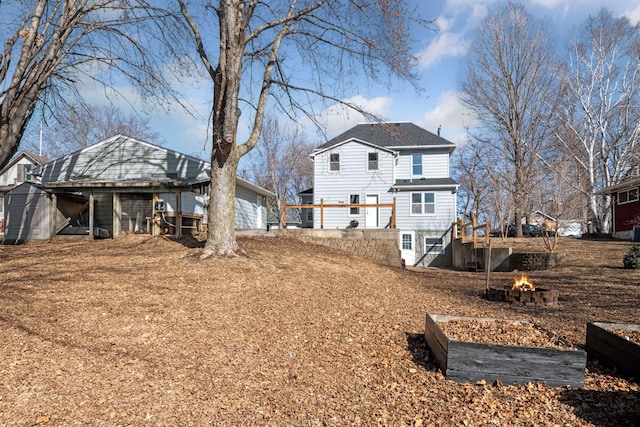 rear view of property featuring a storage unit, an outdoor fire pit, and an outdoor structure