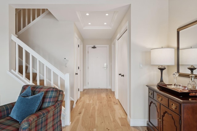 hall featuring a tray ceiling, recessed lighting, stairway, light wood-type flooring, and baseboards