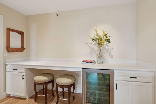 bar with wine cooler and light wood-style flooring