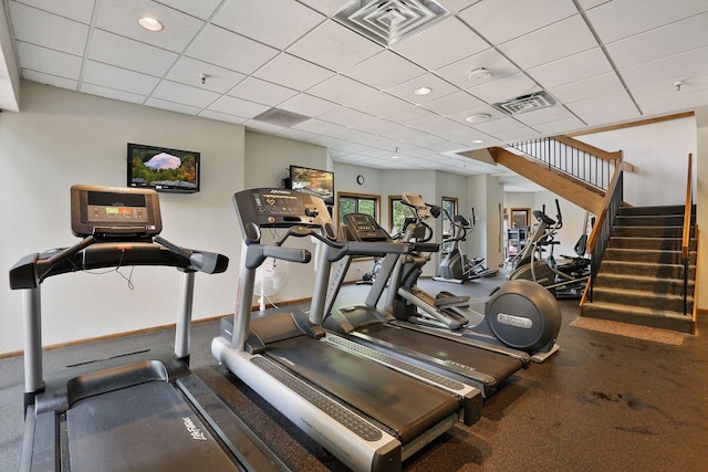 exercise room featuring a paneled ceiling, visible vents, and baseboards