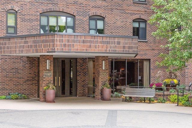 doorway to property with brick siding and a balcony