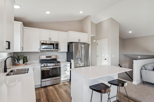 kitchen featuring vaulted ceiling, appliances with stainless steel finishes, a sink, and white cabinets