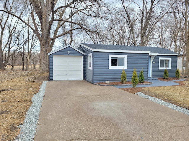 view of front of house featuring an outbuilding, concrete driveway, and roof with shingles