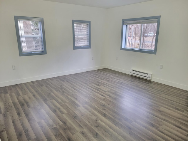 empty room featuring a baseboard radiator, dark wood finished floors, and baseboards