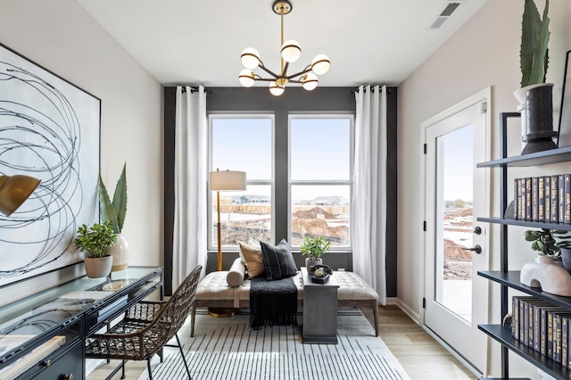 dining space with baseboards, light wood-style flooring, visible vents, and a notable chandelier